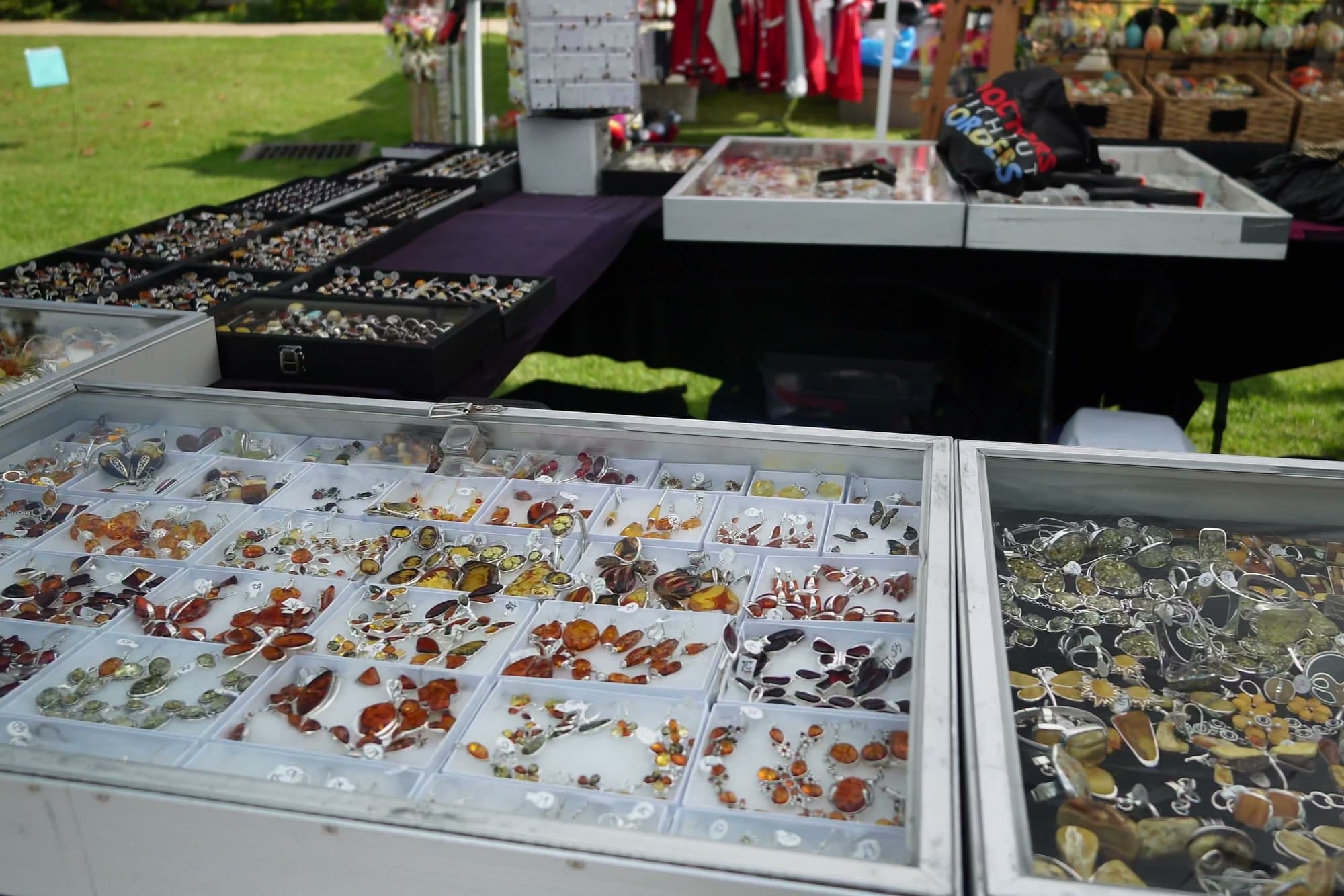 Glass cases of Baltic amber jewellery on a market table, pendants and brooches laid out in rows of honey and cognac tones.
