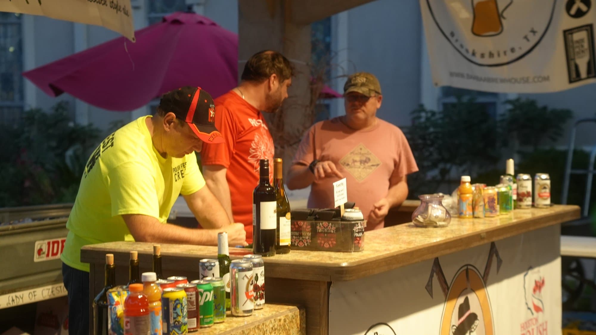Volunteers in neon yellow and orange shirts working the drinks bar, its counter built on stacked hay bales and lined with wine bottles, cans and mixers.