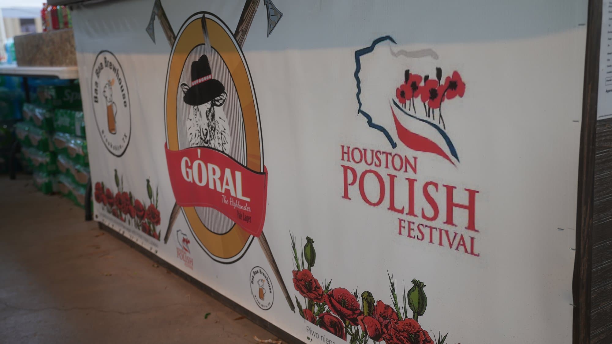 The festival banner: a Góral roundel showing a highlander in a black hat, beside the words Houston Polish Festival and a red outline of Poland, with red poppies and seed pods along the bottom edge.